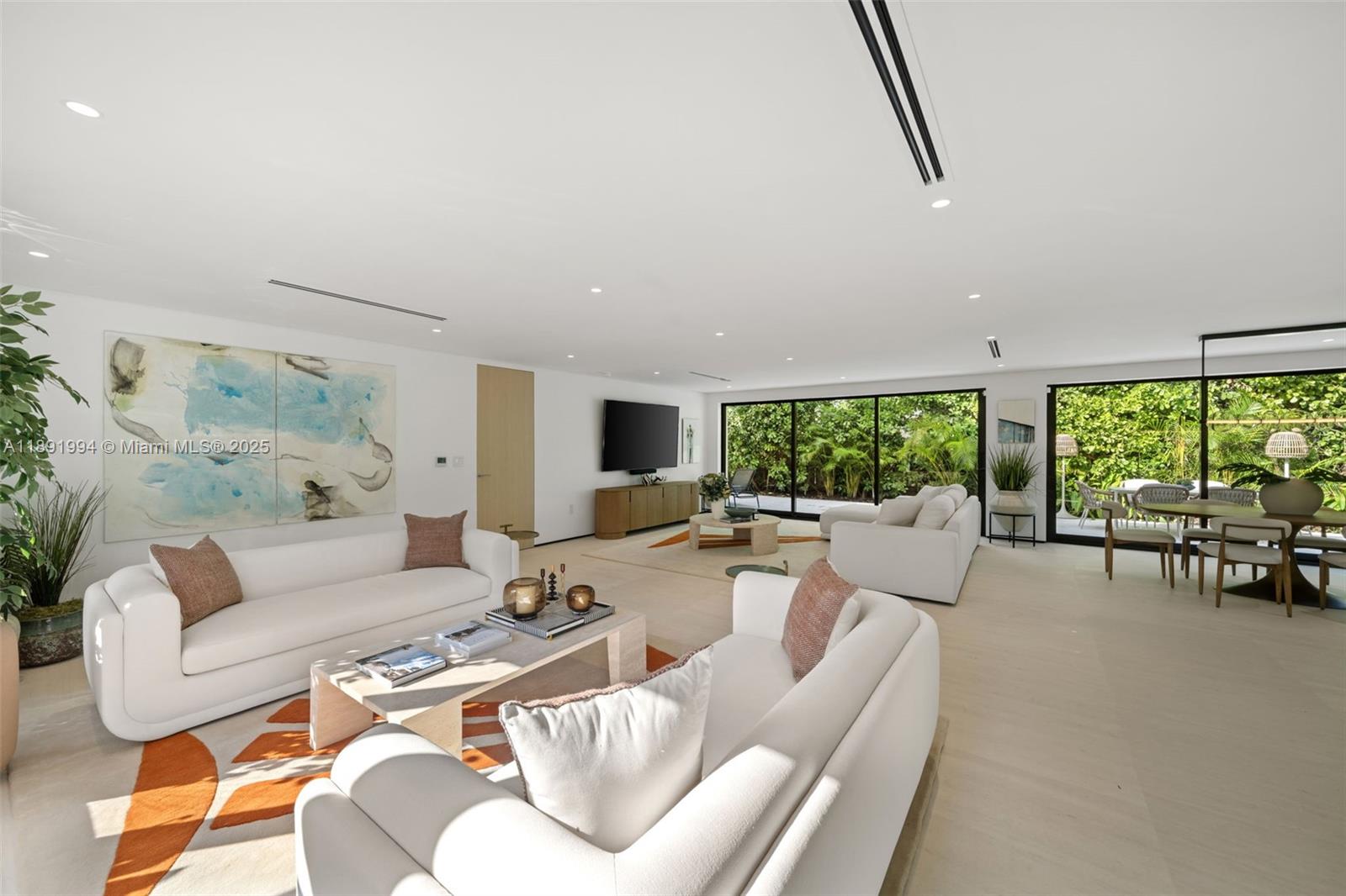 A bright, modern living room features white sofas, a coffee table, and large glass doors — 222 E Rivo Alto Dr, Miami Beach FL 33139, MIAMI BEACH, FL