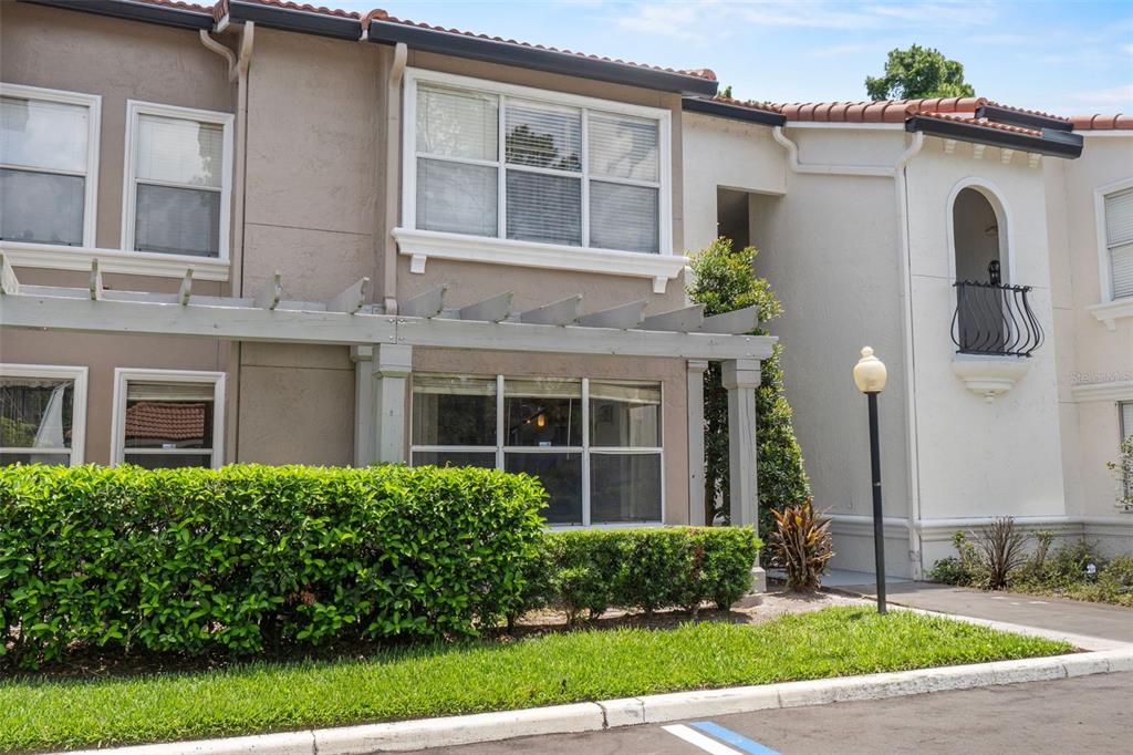 The exterior of a two-story residential building features a pergola, hedges, and a small balcony — 5116 CONROY ROAD UNIT 15, ORLANDO, FL