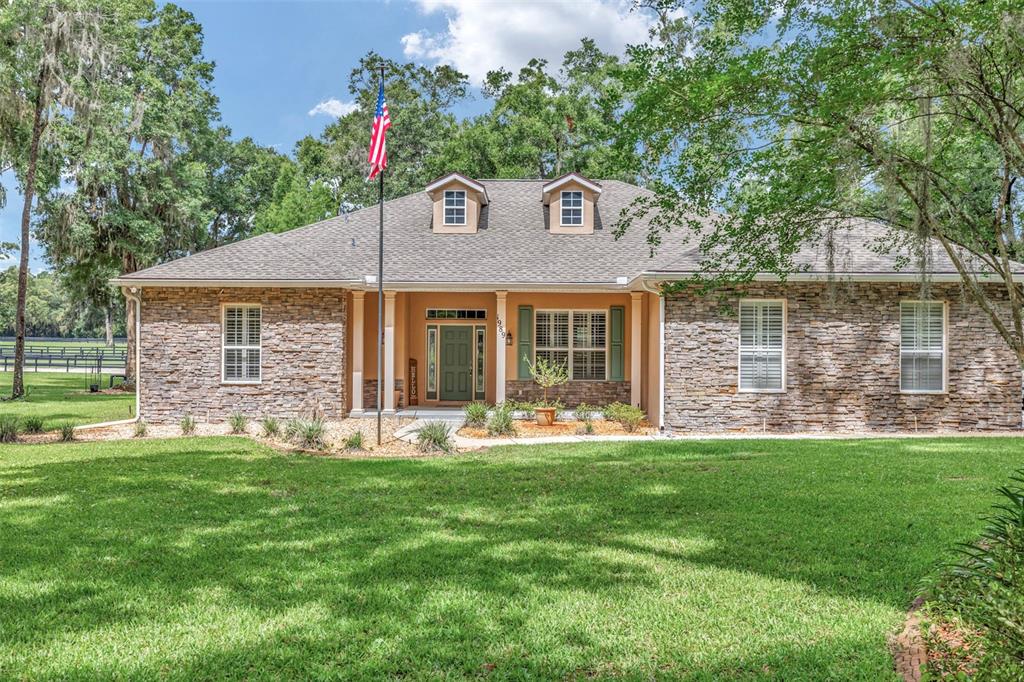 A single-story stone-veneer house with a flag pole and two dormer windows on the roof — 1989 NW 111TH LOOP, OCALA, FL