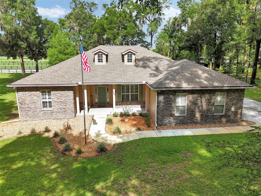 A single-story house with a stone facade, a shingled roof, and a front yard — 1989 NW 111TH LOOP, OCALA, FL