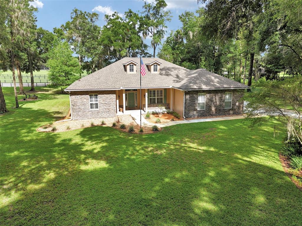 A single-story house with stone veneer siding, a shingled roof, and a front lawn — 1989 NW 111TH LOOP, OCALA, FL
