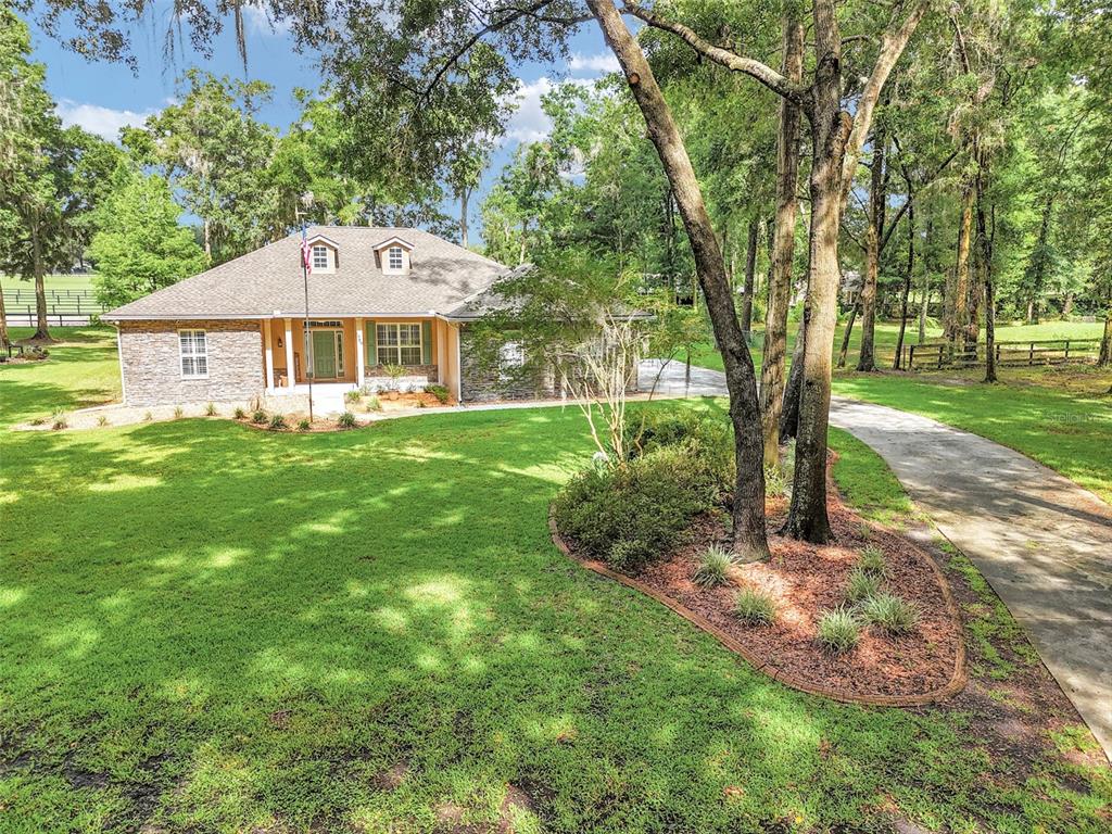 A single-story house with a stone facade and a concrete driveway sits on a lawn — 1989 NW 111TH LOOP, OCALA, FL