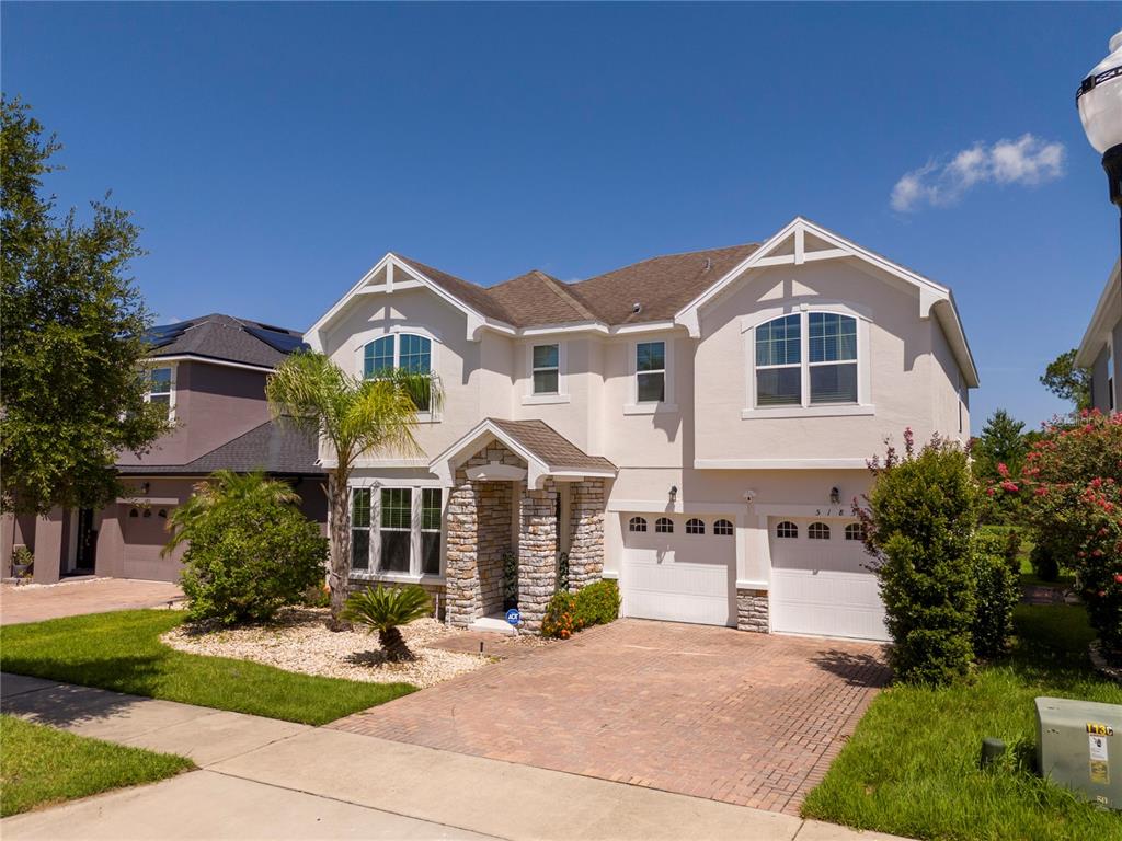 A two-story suburban house with a stone-accented entryway and a two-car garage — 5185 DOVE TREE STREET, ORLANDO, FL