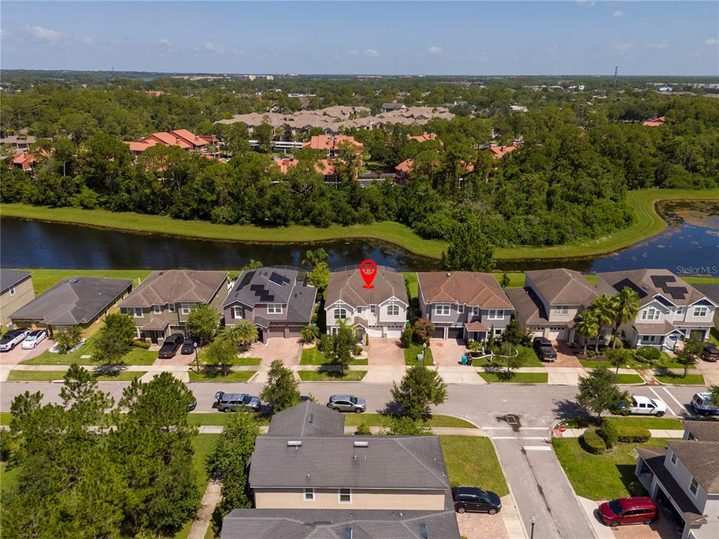 An aerial view shows a suburban neighborhood with houses, a canal, and trees — 5185 DOVE TREE STREET, ORLANDO, FL