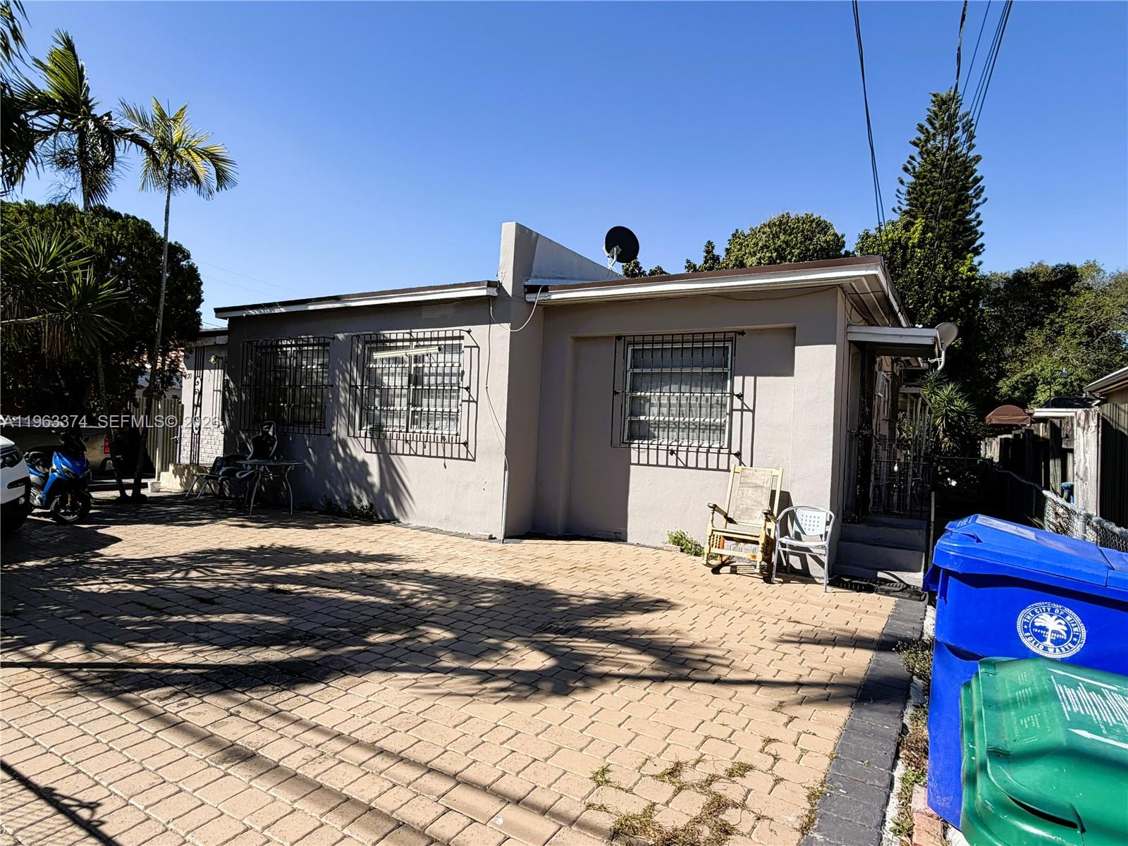 A single-story house with a paved driveway, security bars on windows, and two trash bins — 430 NW 53rd Ave, Miami FL 33126, MIAMI, FL