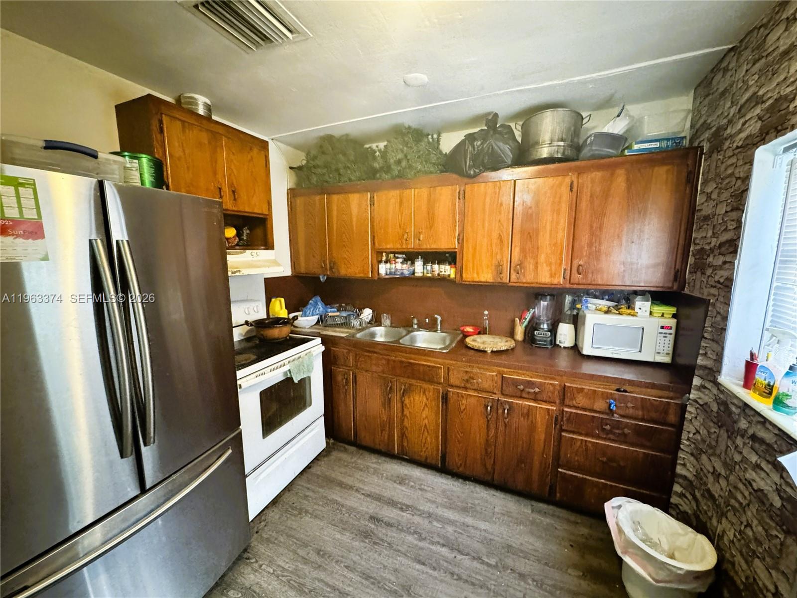 A kitchen features wooden cabinets, a stainless steel refrigerator, a white stove, and a sink — 430 NW 53rd Ave, Miami FL 33126, MIAMI, FL