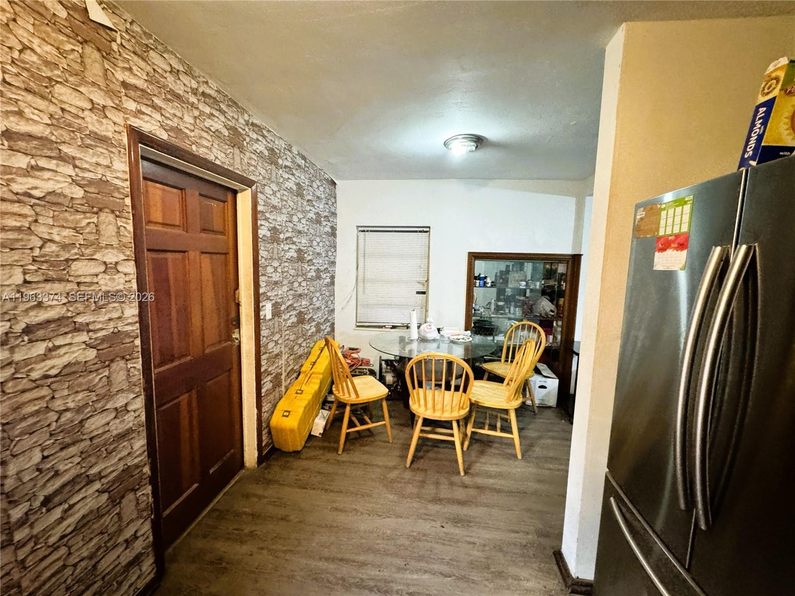 A dining area features a glass table, wooden chairs, and a stone-patterned accent wall — 430 NW 53rd Ave, Miami FL 33126, MIAMI, FL