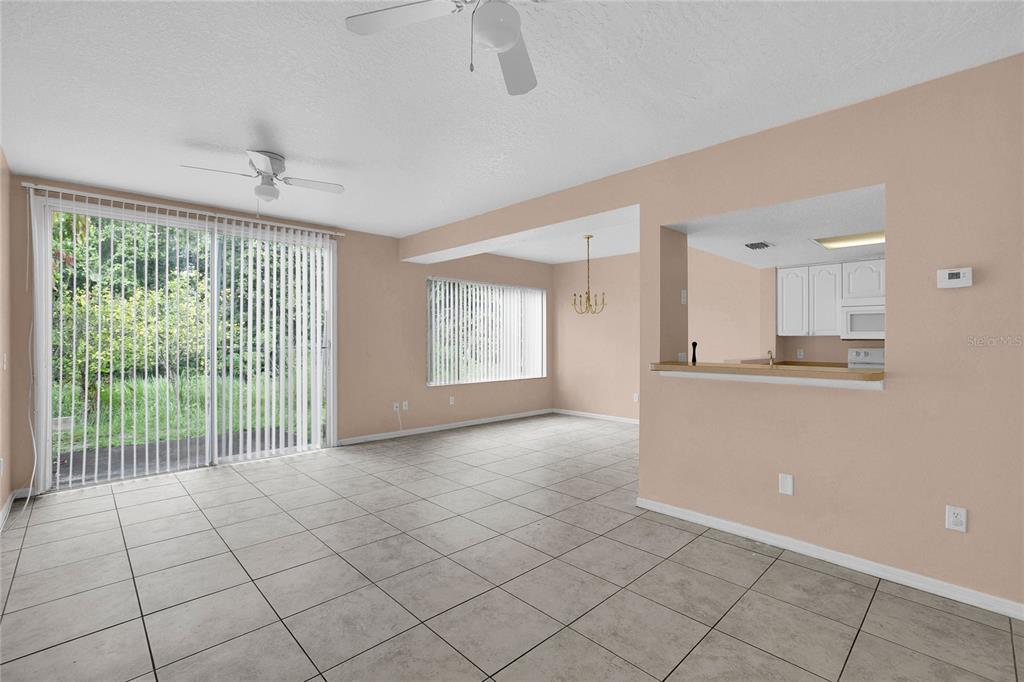 An open-concept living and dining area features tile flooring, ceiling fans, and a kitchen pass-through — 2918 FAN PALM DRIVE UNIT Main, DAVENPORT, FL