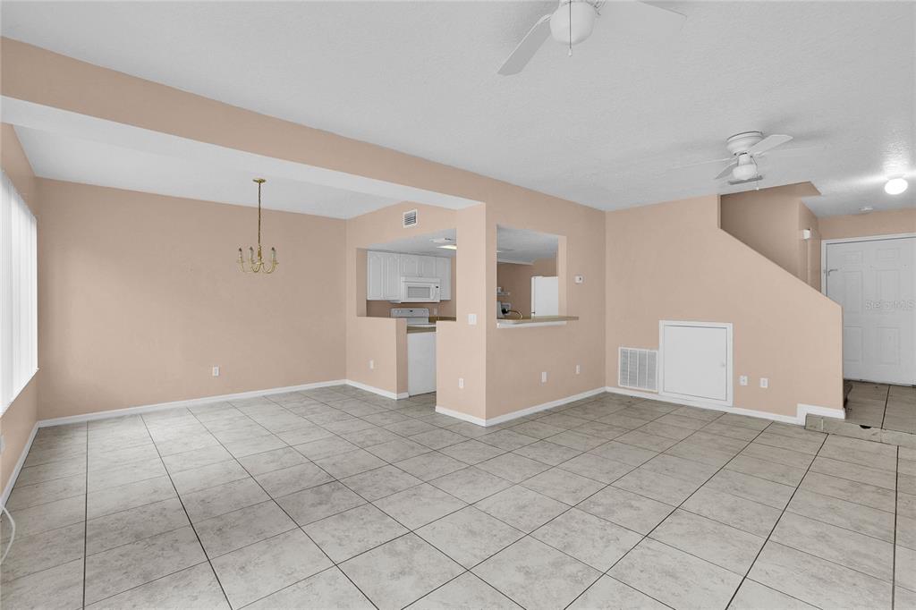 An open-concept living and dining area features light-colored tile flooring and a pass-through kitchen window — 2918 FAN PALM DRIVE UNIT Main, DAVENPORT, FL