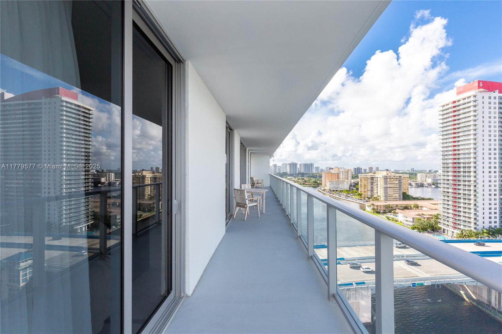 A long, narrow balcony with a glass railing overlooks a waterway and city skyline — 4010 S Ocean Dr # R2204, Hollywood FL 33019, HOLLYWOOD, FL