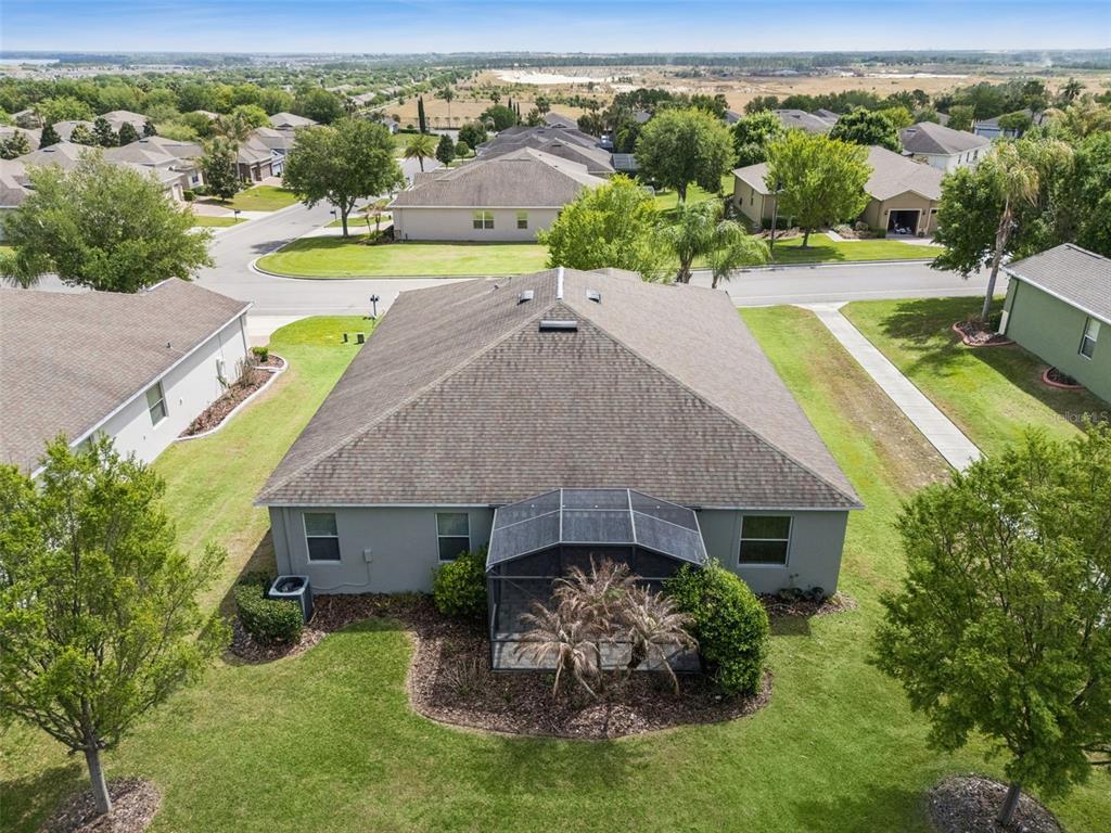 An aerial view of a suburban house with a screened-in patio and a hip roof — 3859 SANIBEL STREET, CLERMONT, FL