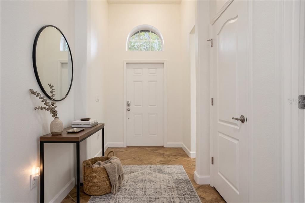 A bright entryway features a console table, a round mirror, and a white front door — 3859 SANIBEL STREET, CLERMONT, FL