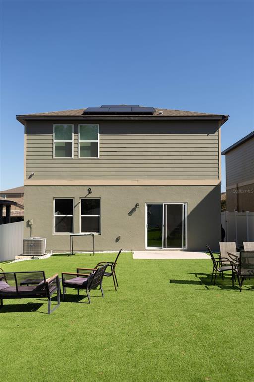 The exterior rear view of a two-story house features a lawn, patio furniture, and solar panels — 2015 HEMINGWAY CIRCLE, GROVELAND, FL