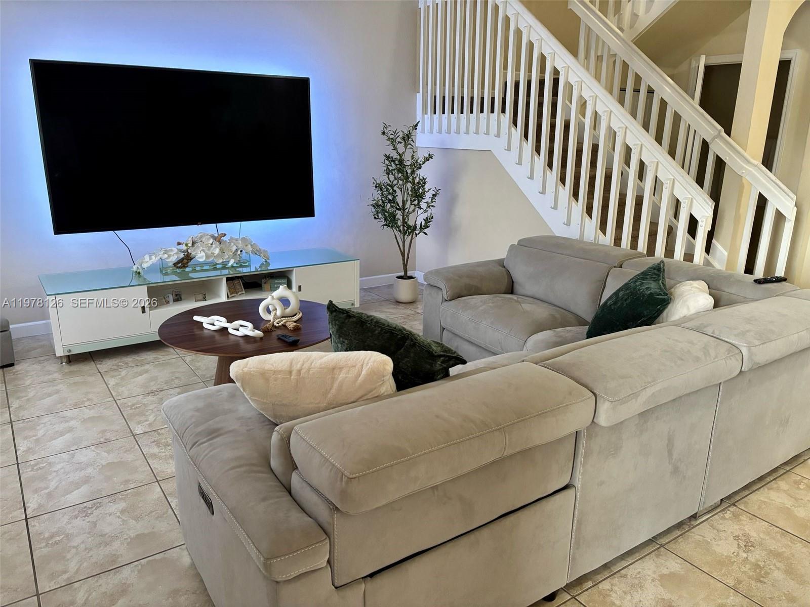 A living room features a large television, a gray sectional sofa, and a staircase — 3544 W 88th Ter, Hialeah FL 33018, HIALEAH, FL