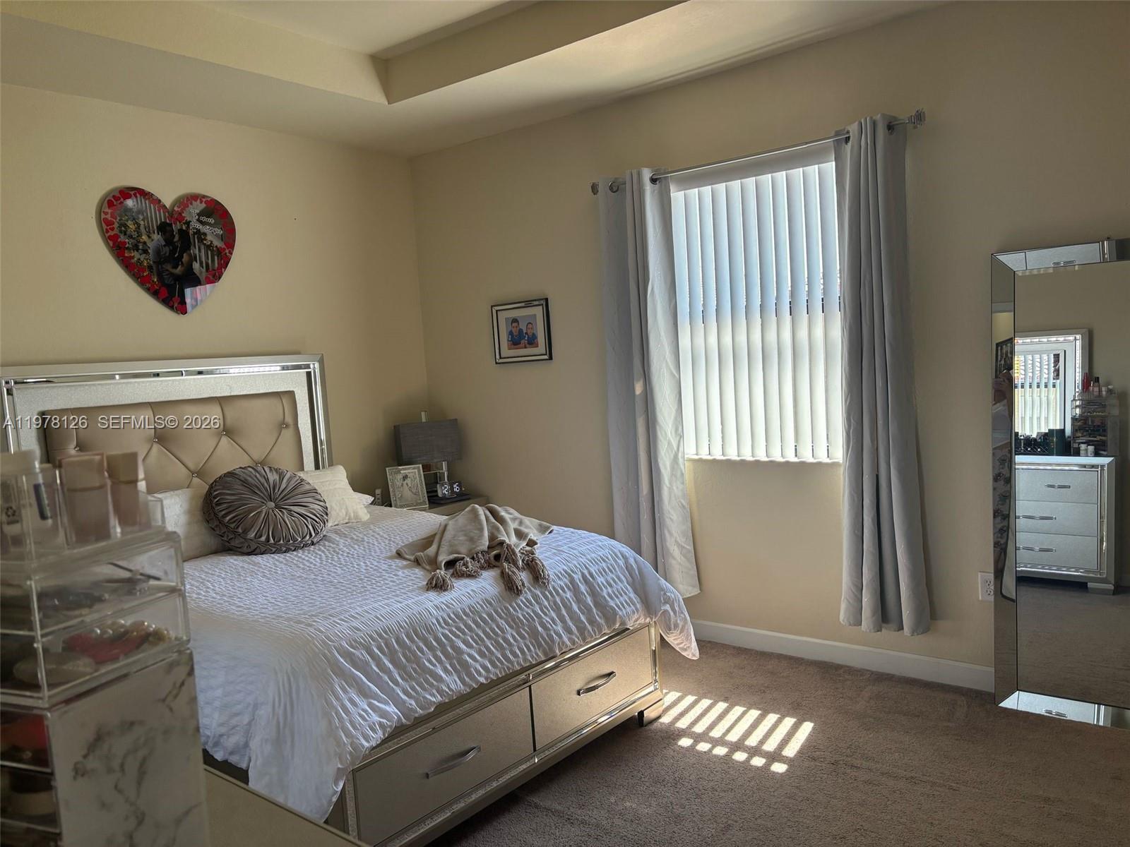 A bedroom features a tufted headboard, a mirrored dresser, a window with blinds, and carpet — 3544 W 88th Ter, Hialeah FL 33018, HIALEAH, FL