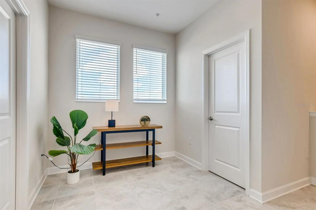 A room with light tile flooring, two windows, a wooden console table, and a plant — 545 OCEAN COURSE AVENUE UNIT 545, DAVENPORT, FL