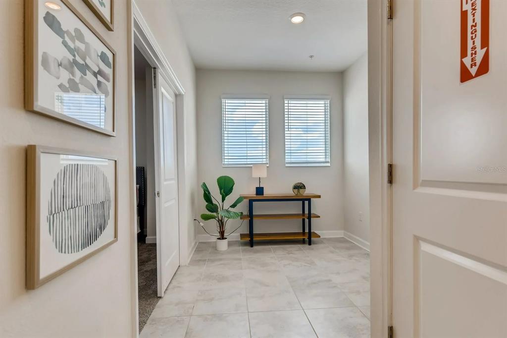 A tiled hallway leads to a small room featuring two windows, a console table, and plants — 545 OCEAN COURSE AVENUE UNIT 545, DAVENPORT, FL