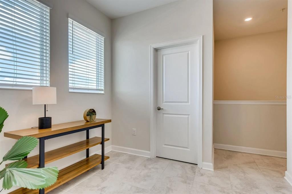 A room with light tile flooring, a wooden console table, a lamp, and a white door — 545 OCEAN COURSE AVENUE UNIT 545, DAVENPORT, FL
