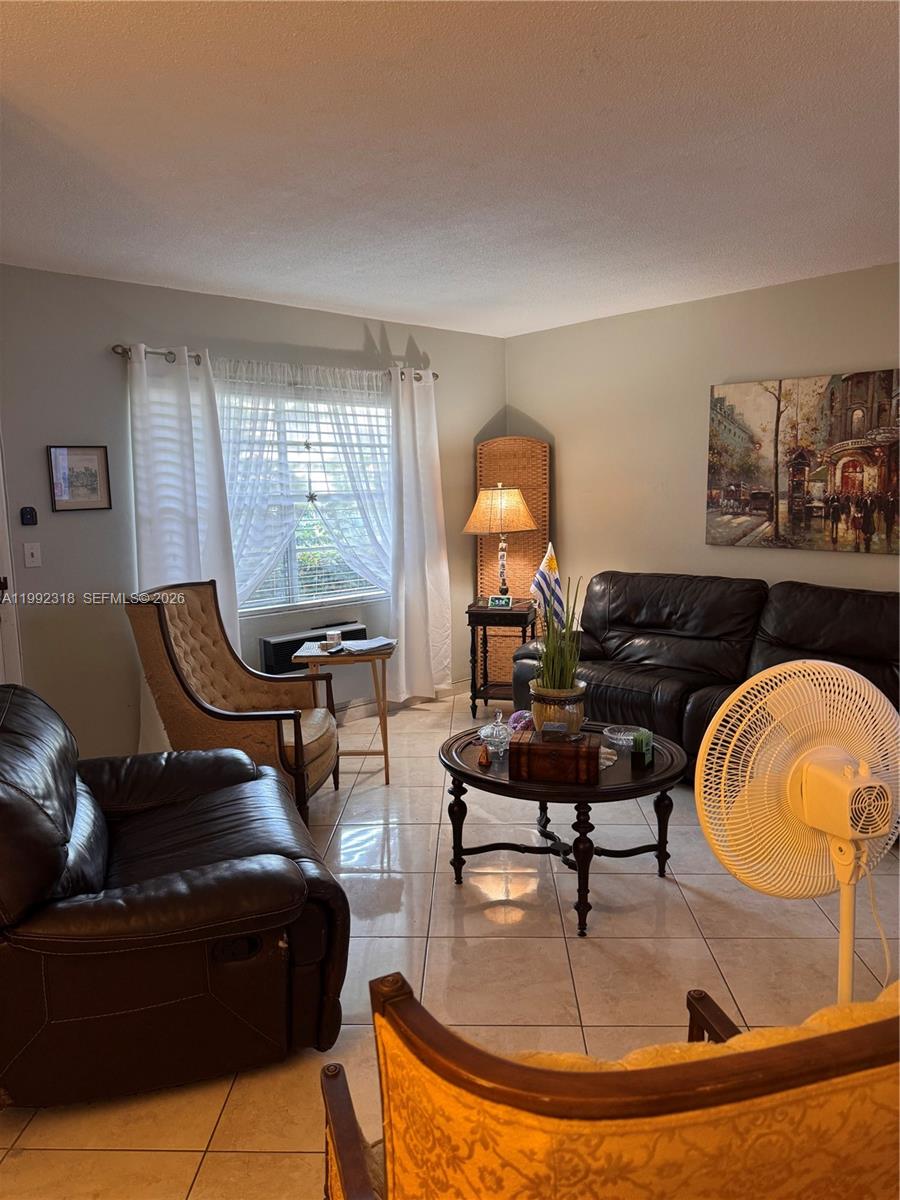 A living room features tile flooring, leather furniture, a round coffee table, and a window — 17090 NE 14th Ave # 107, Miami FL 33162, MIAMI, FL