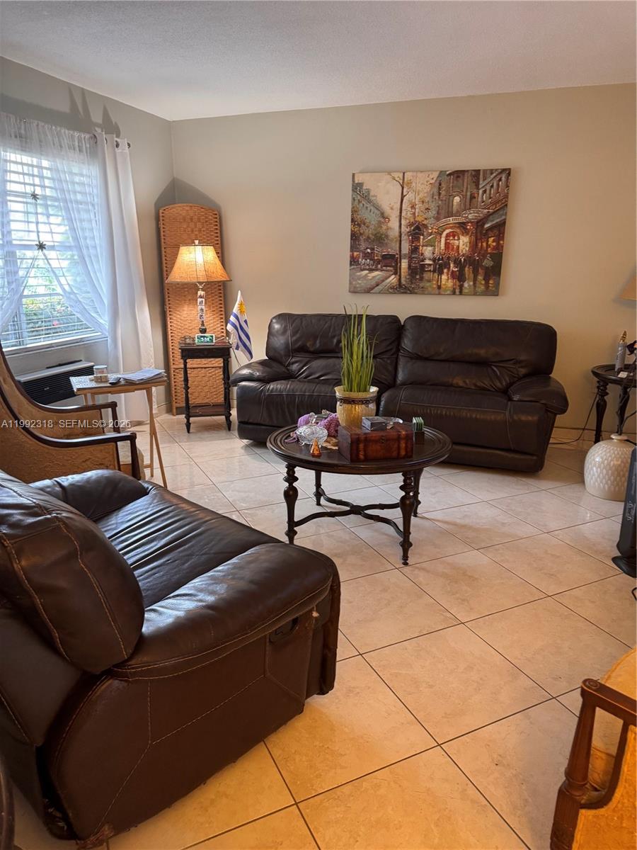 A living room features two dark leather sofas, a round coffee table, and tile flooring — 17090 NE 14th Ave # 107, Miami FL 33162, MIAMI, FL