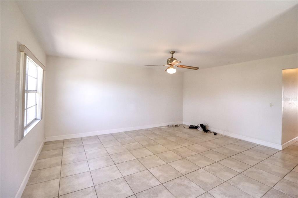 An empty room features light-colored tile flooring, white walls, and a ceiling fan — 302 CANTON COURT UNIT 59, SUN CITY CENTER, FL