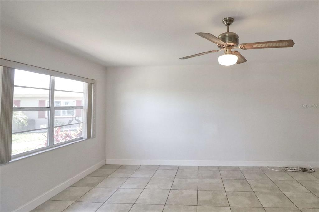 A room with light-colored tile flooring, white walls, a ceiling fan, and a large window — 302 CANTON COURT UNIT 59, SUN CITY CENTER, FL