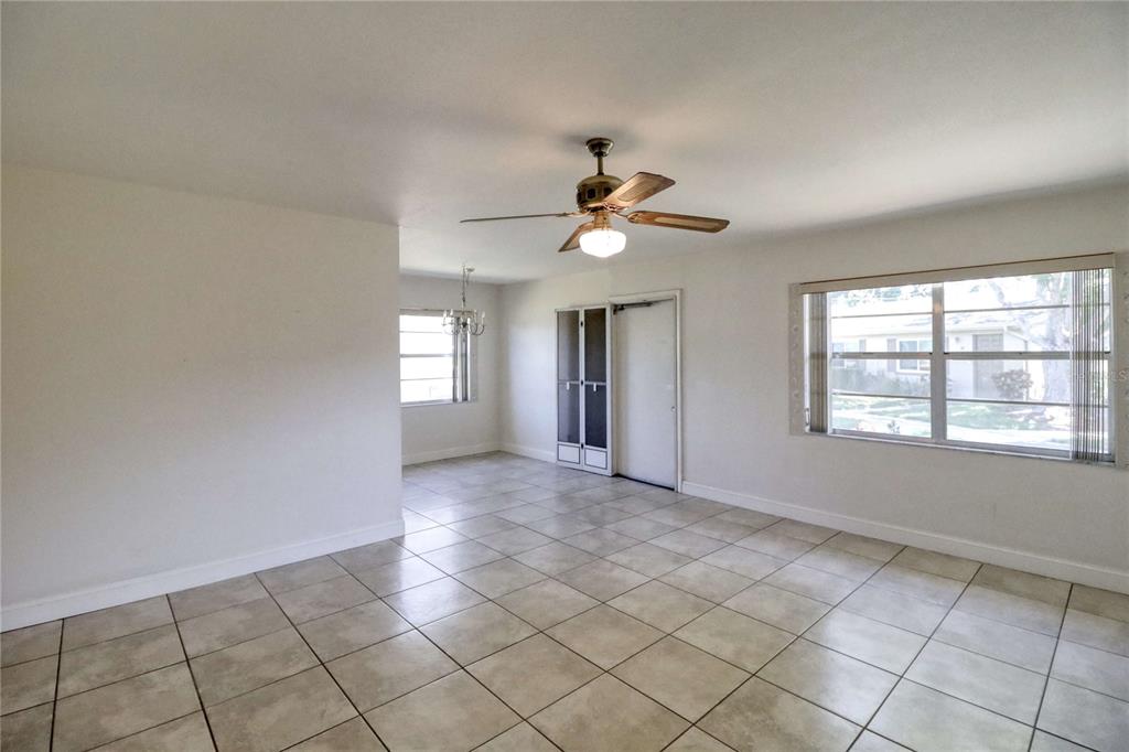 An empty room with light-colored tile flooring, a ceiling fan, and large windows — 302 CANTON COURT UNIT 59, SUN CITY CENTER, FL