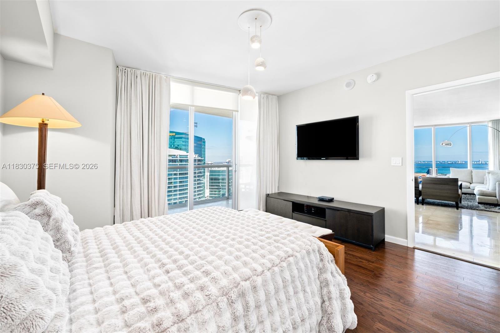 A bedroom with a textured white bedspread, dark wood floors, and a balcony with city views — 465 Brickell Ave # 5302, Miami FL 33131, MIAMI, FL