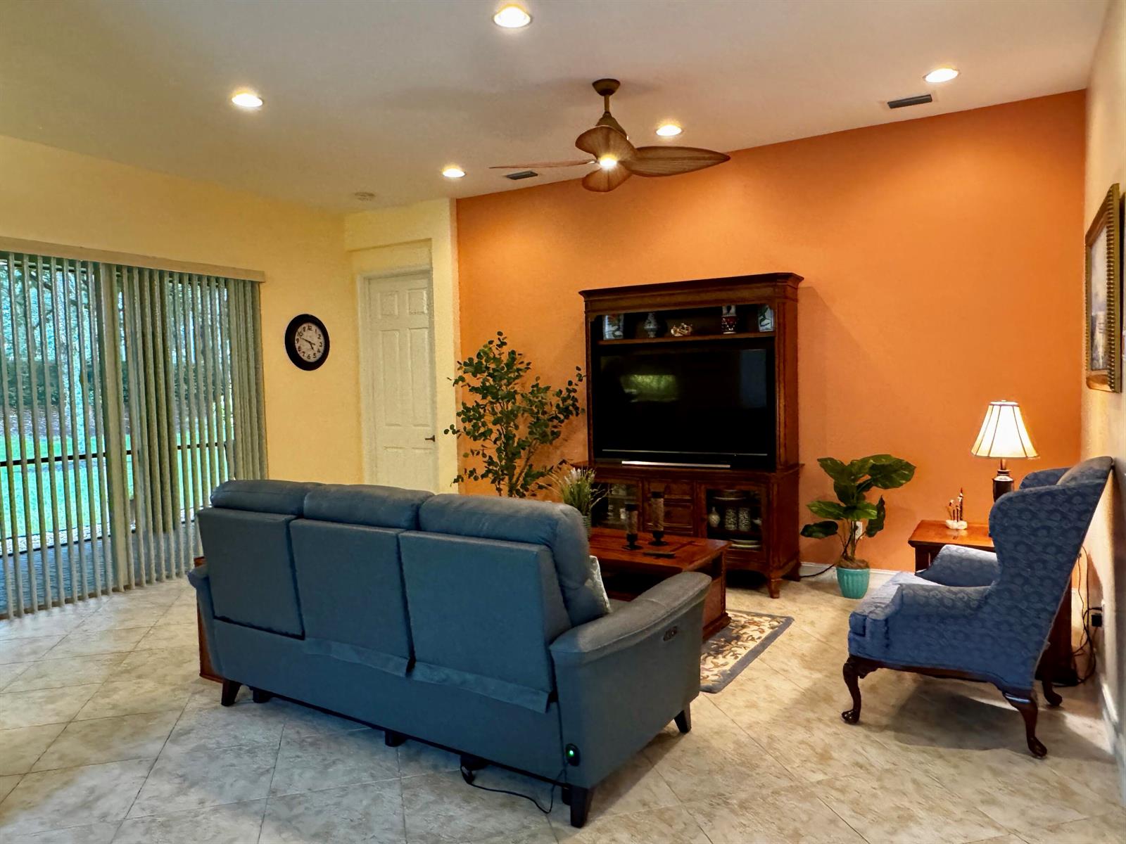A living room features a blue sofa, a wingback chair, and a large wooden entertainment center — 9385 Ivory Isle Road, Boynton Beach FL 33473, BOYNTON BEACH, FL