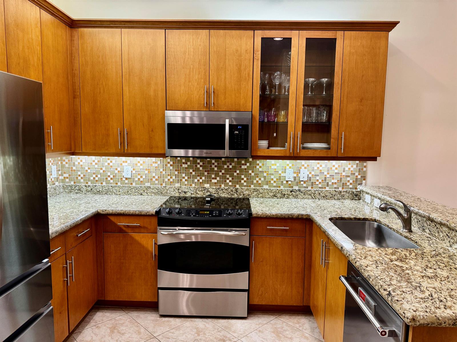 A kitchen featuring wood cabinets, granite countertops, stainless steel appliances, and a mosaic tile backsplash — 9385 Ivory Isle Road, Boynton Beach FL 33473, BOYNTON BEACH, FL