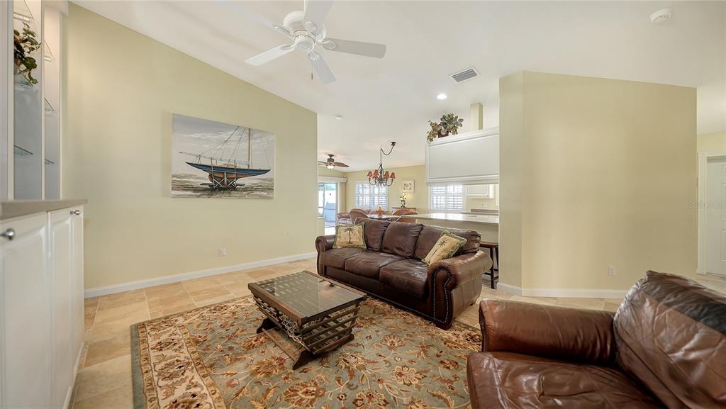 A living room features a brown leather sofa, a patterned rug, and tile flooring — 11641 GARESSIO LANE, SARASOTA, FL