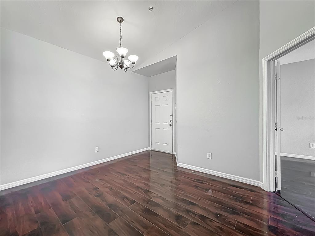 An empty room with dark wood flooring, light gray walls, and a hanging chandelier — 2615 MAITLAND CROSSING WAY UNIT 9 307, ORLANDO, FL