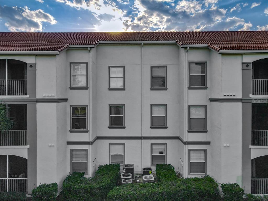 A three-story apartment building exterior features white stucco walls, a tiled roof, and balconies — 2615 MAITLAND CROSSING WAY UNIT 9 307, ORLANDO, FL