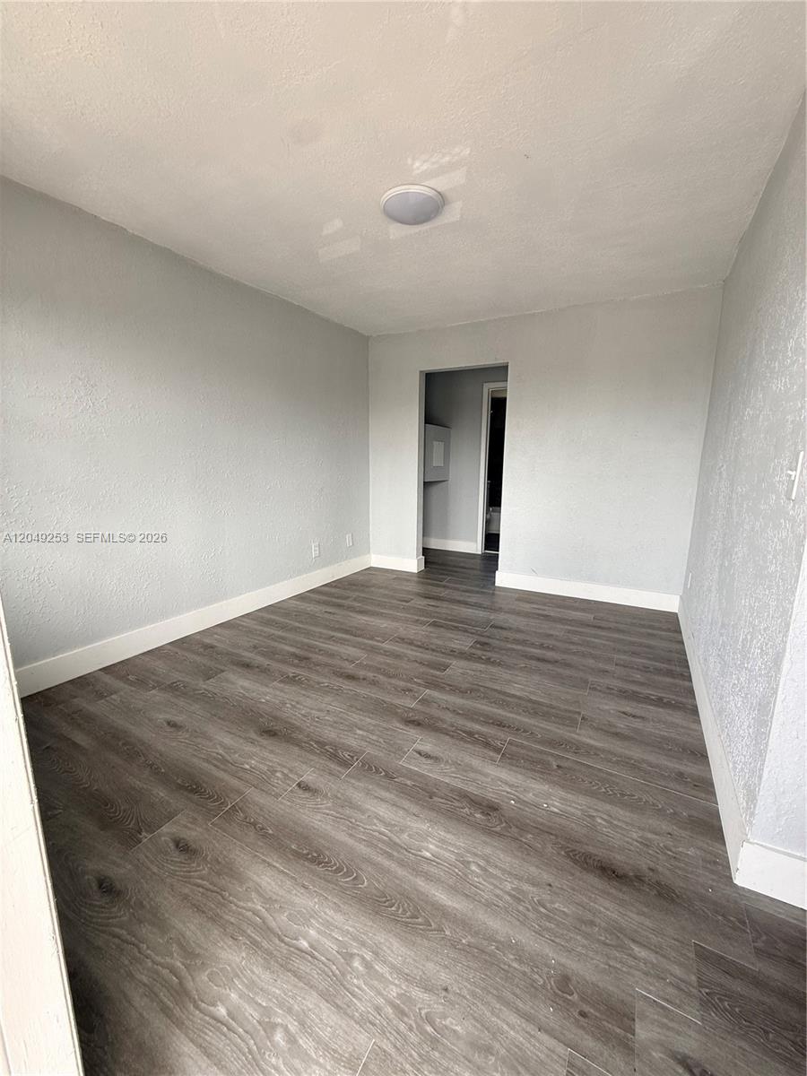 An empty room features light gray walls, white baseboards, and wood-look laminate flooring — 7001 NW 15th Ave # 4, Miami FL 33147, MIAMI, FL