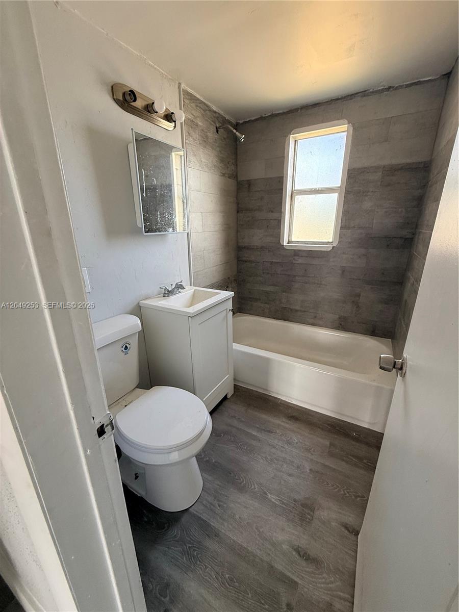 A small bathroom features a toilet, a white vanity, and a tub with tiled walls — 7001 NW 15th Ave # 4, Miami FL 33147, MIAMI, FL