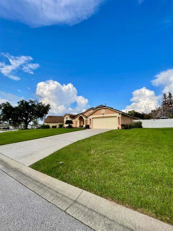 A single-story house with a tan exterior and a two-car garage sits on a lawn — 254 LOMA DEL SOL DRIVE, DAVENPORT, FL