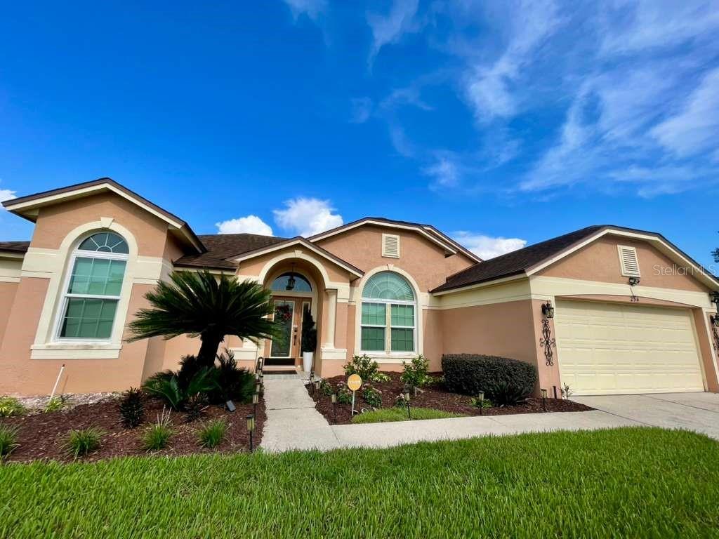 A single-story house with a tan stucco exterior, arched windows, and a two-car garage — 254 LOMA DEL SOL DRIVE, DAVENPORT, FL