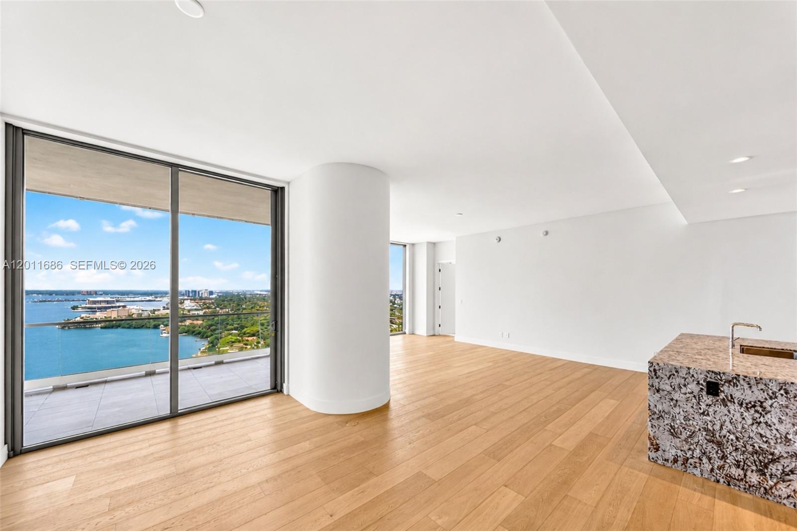 An empty living area features light wood floors, a large structural column, and floor-to-ceiling windows — 175 25 RD # 3303, Miami FL 33129, MIAMI, FL