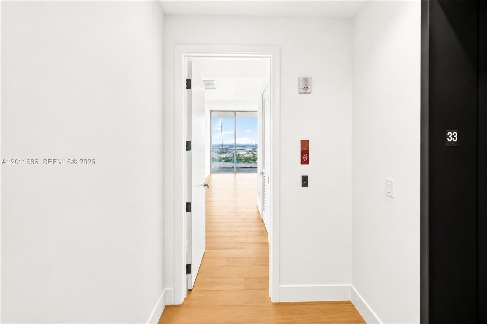 A hallway leads to a room with floor-to-ceiling windows overlooking a harbor — 175 25 RD # 3303, Miami FL 33129, MIAMI, FL