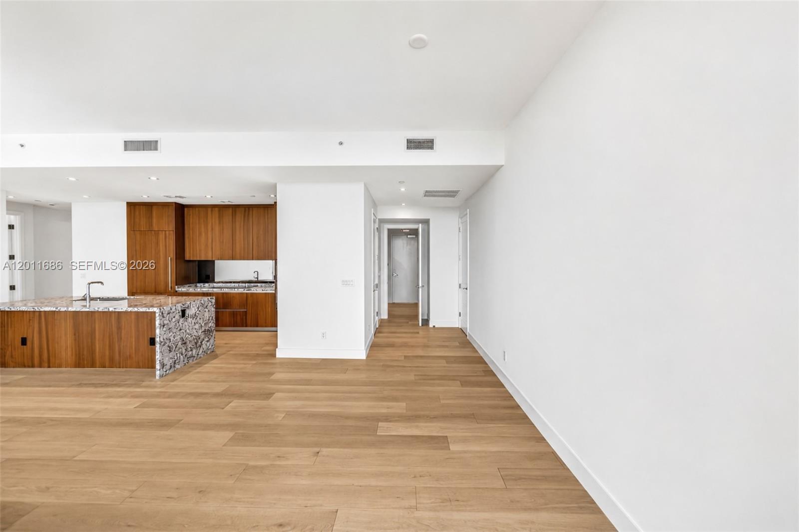 A modern kitchen with wood cabinetry and a stone island opens to a living area — 175 25 RD # 3303, Miami FL 33129, MIAMI, FL