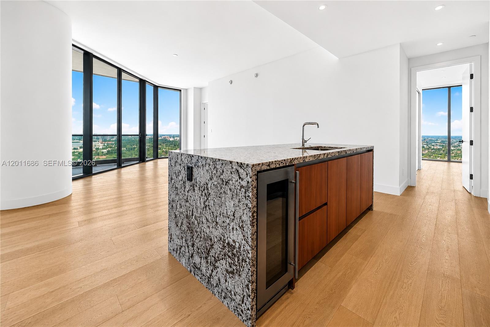 A modern kitchen island with a granite countertop sits in a room with floor-to-ceiling windows — 175 25 RD # 3303, Miami FL 33129, MIAMI, FL