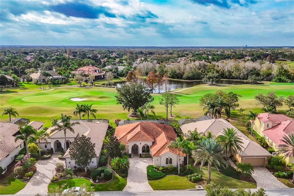 An aerial view of suburban houses with tile roofs overlooking a golf course and pond — 7042 VILAMOURA PLACE, LAKEWOOD RANCH, FL