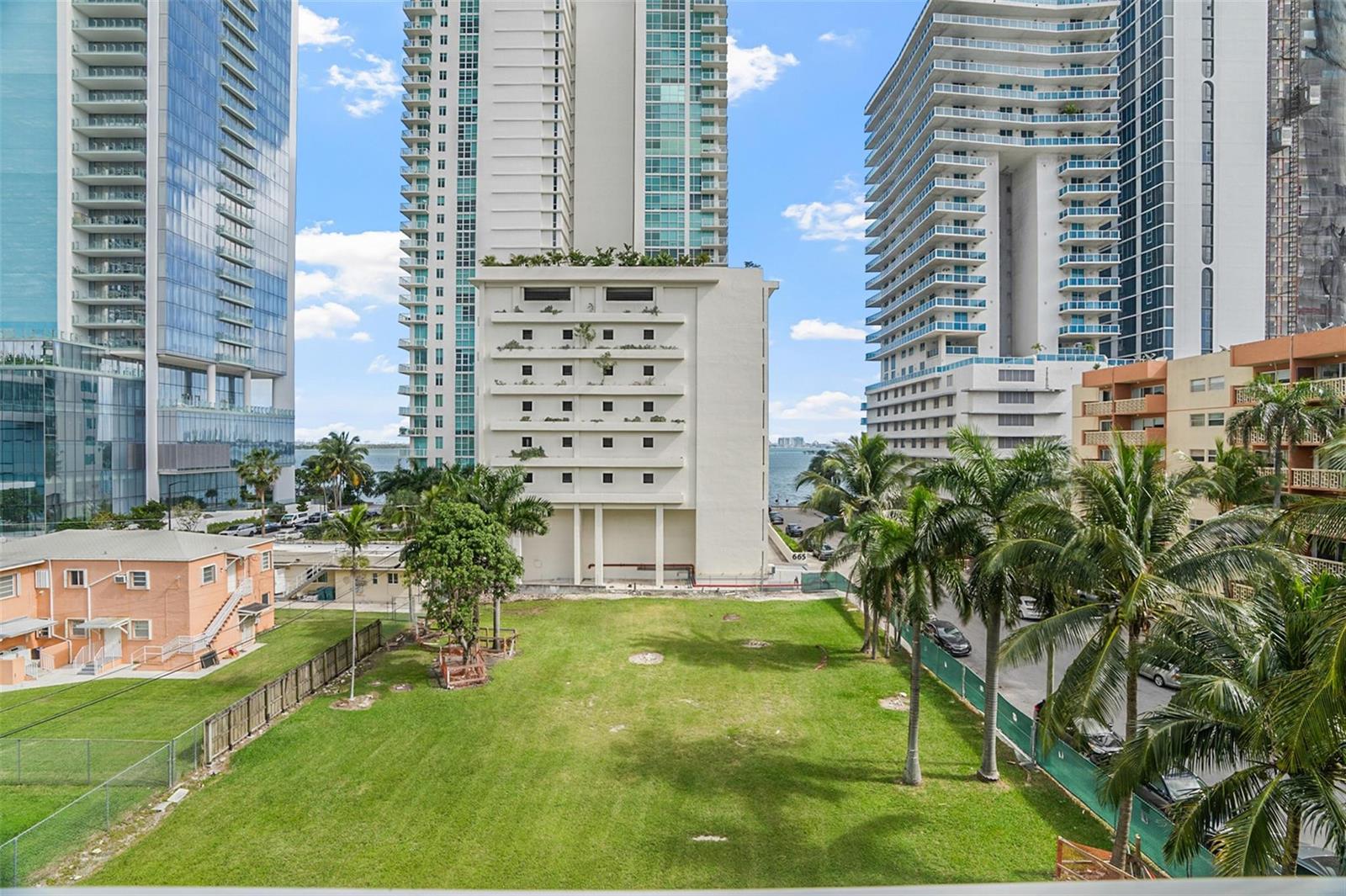 An elevated view shows a grassy vacant lot surrounded by tall residential buildings and palm trees — 471 NE 25th Street # 503, Miami FL 33137, MIAMI, FL