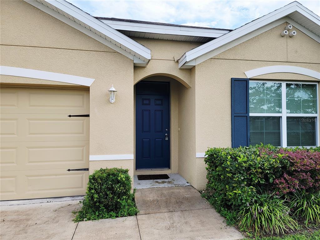 The exterior of a beige house features a blue front door and a garage — 4986 SW 97TH PLACE, OCALA, FL
