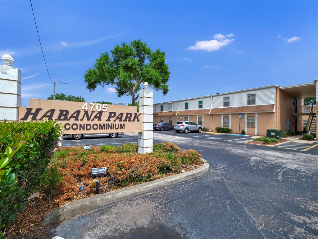 The exterior of a two-story condominium complex features a parking lot and a prominent sign — 4724 CHRISTA COURT UNIT 322, TAMPA, FL