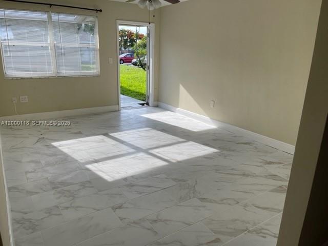 An empty room features white marble-look tile flooring, light-colored walls, and a glass door — 7601 Venetian St # 4, Miramar FL 33023, MIRAMAR, FL
