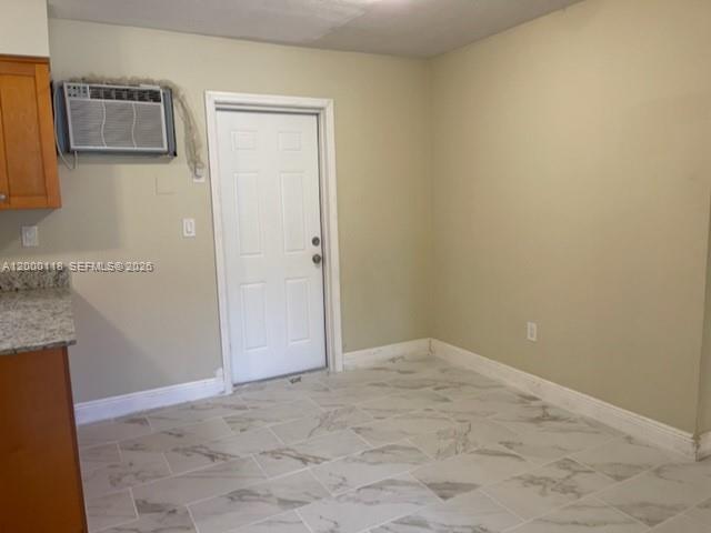 A room with light-colored walls, marble-patterned tile flooring, a white door, and a window air conditioner — 7601 Venetian St # 4, Miramar FL 33023, MIRAMAR, FL