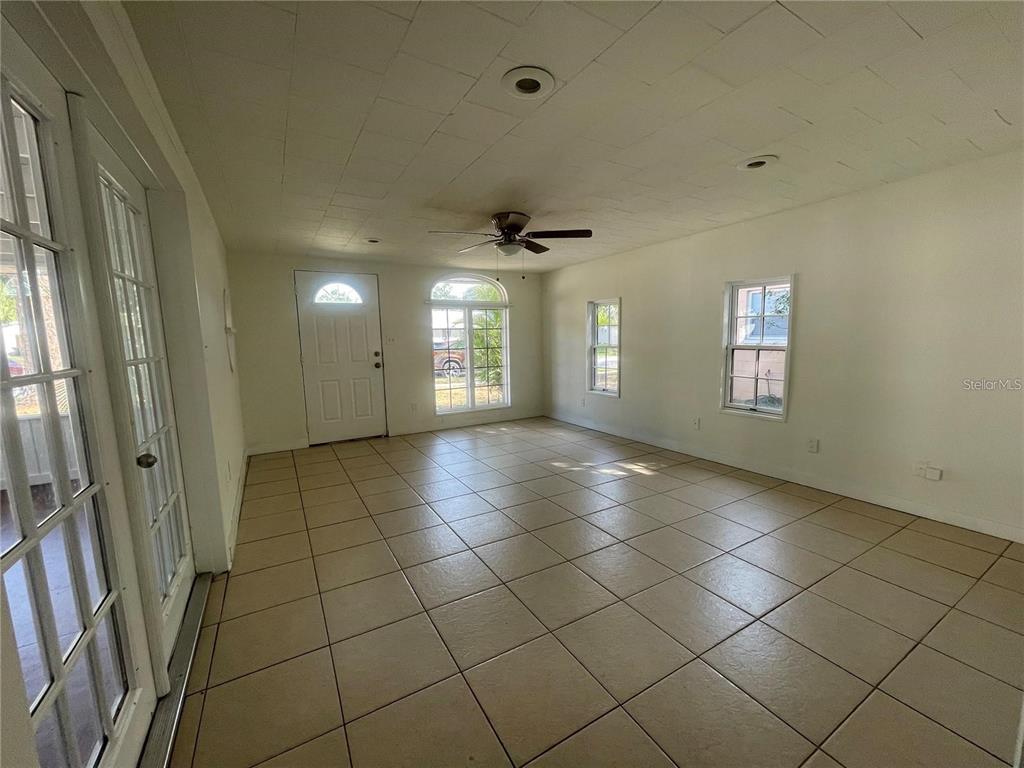 A spacious room with white walls, tile flooring, a ceiling fan, and multiple windows — 5891 93RD AVENUE N, PINELLAS PARK, FL