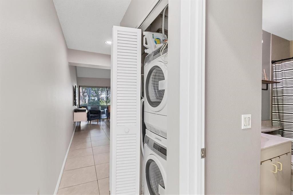 A stacked washer and dryer are located in a closet next to a bathroom — 4717 WINSLOW BEACON UNIT 7, SARASOTA, FL