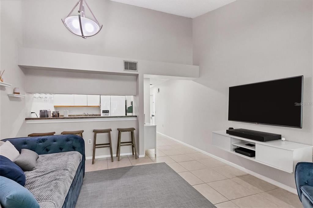 A living room features a blue sofa, a wall-mounted television, and a breakfast bar — 4717 WINSLOW BEACON UNIT 7, SARASOTA, FL